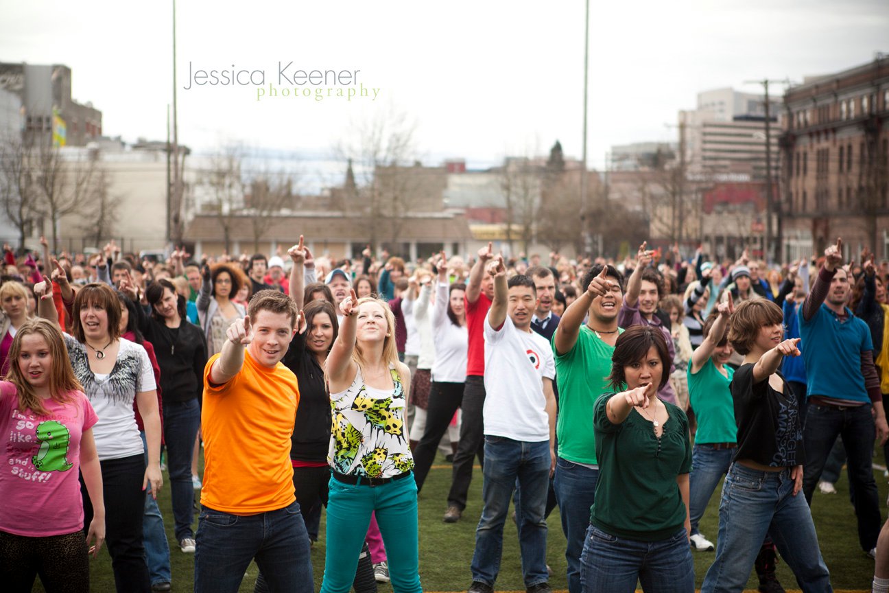 A flash mob crowd of dancers pointing toward the camera