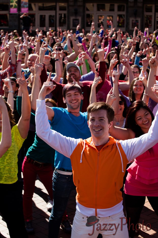 A flash mob crowd of dancers pointing to fingers into the air