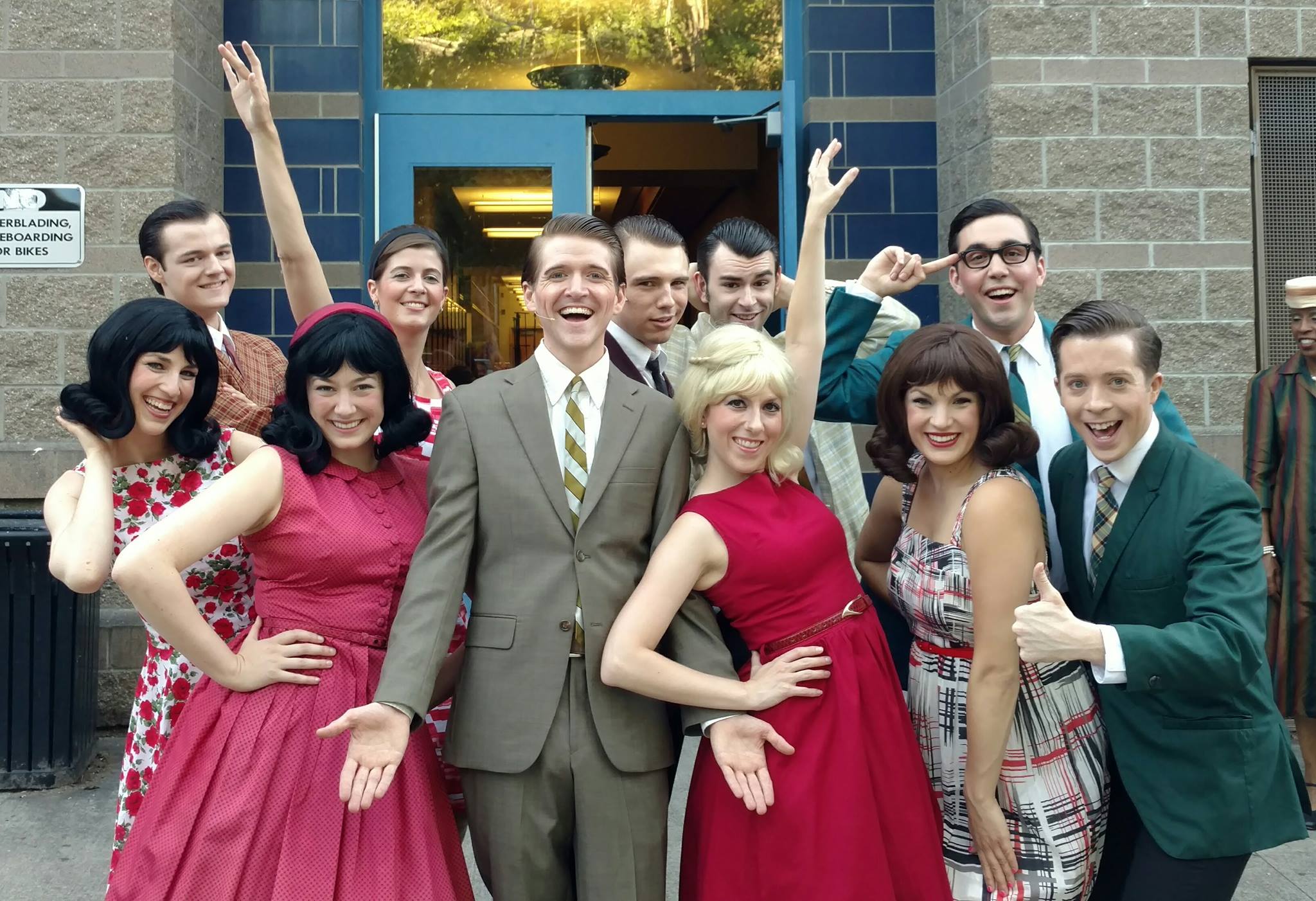 A group of actors dressed in 60s costumes posing with funny faces